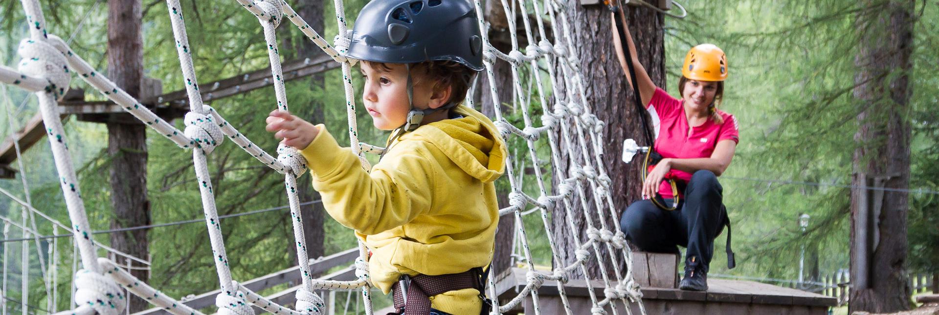 Un bambino piccolo fa arrampicate in un parco avventura